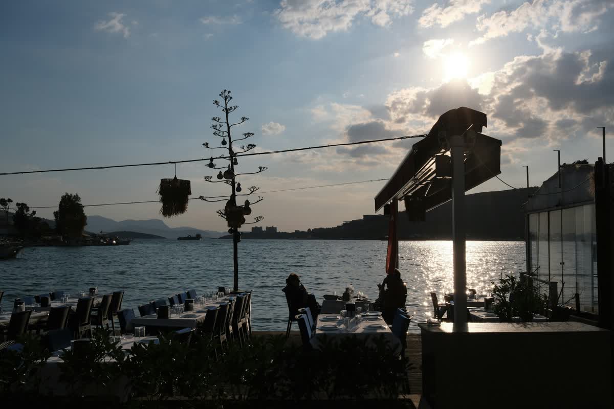 Outdoor restaurant seating at sunset over a bay